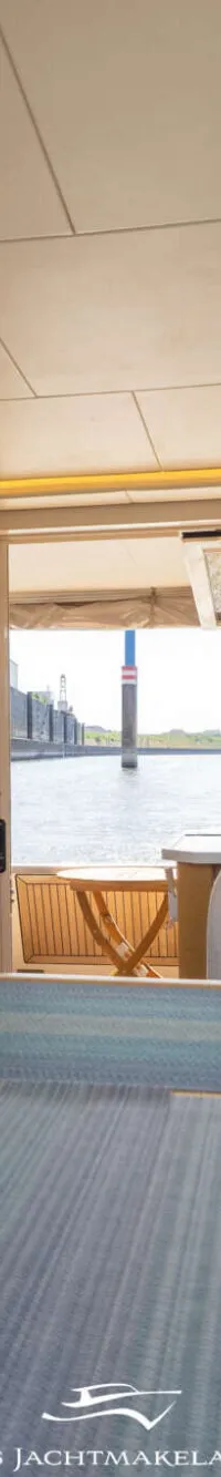 Een interieur van een boot met een houten tafel, banken, een keukenblok en uitzicht op water. — Greenline Greenline 39