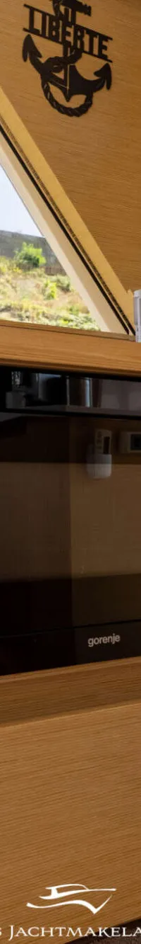 Een ingebouwde Gorenje magnetron in een houten interieur met een raam en decoraties.