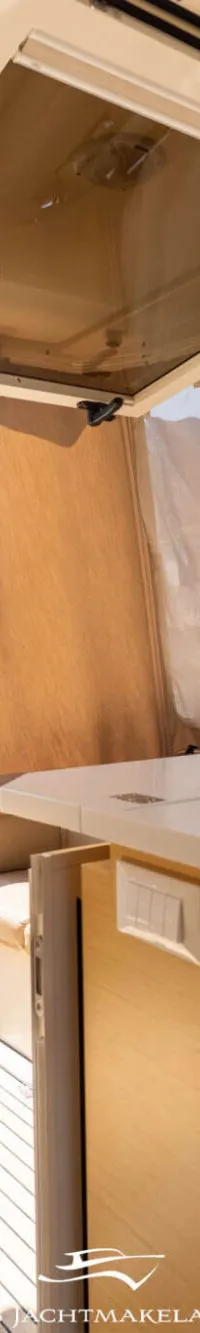 Een bootinterieur met een open achterzijde, een houten klaptafel en een keukenblok met koffiezetapparaat en kookplaat.