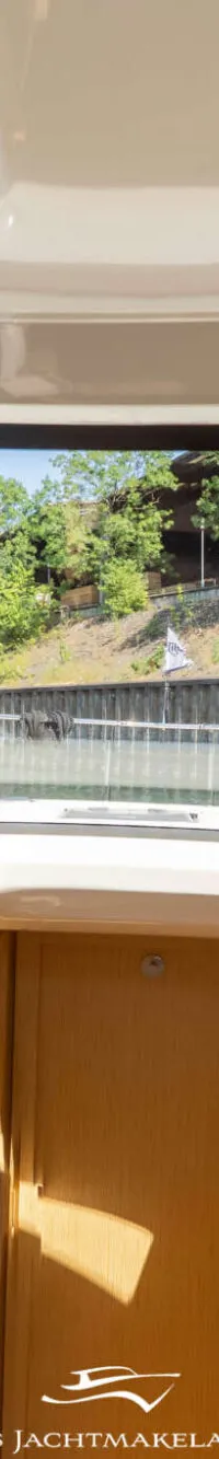 Een interieurfoto van een boot met uitzicht op een kanaal met bebouwing en bomen langs de oever. — Greenline Greenline 39