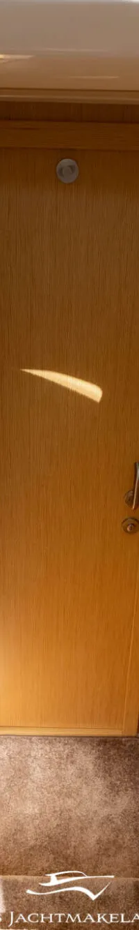 Een houten interieur met een trap naar beneden, een deur en handgrepen.