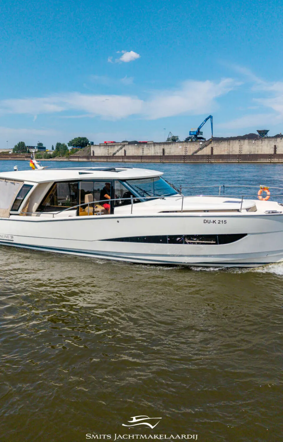 Een witte motorboot met de registratie "DU-K 215" vaart over water met een industriële achtergrond. — Greenline Greenline 39