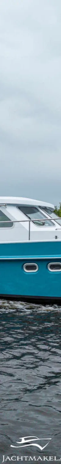 Een blauw-witte motorboot vaart op het water, met een Nederlandse vlag aan de boeg.