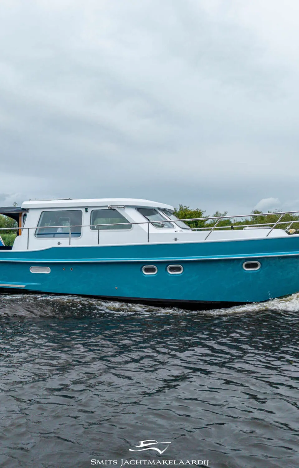 Een blauw-witte motorboot vaart op het water, met een Nederlandse vlag aan de boeg.