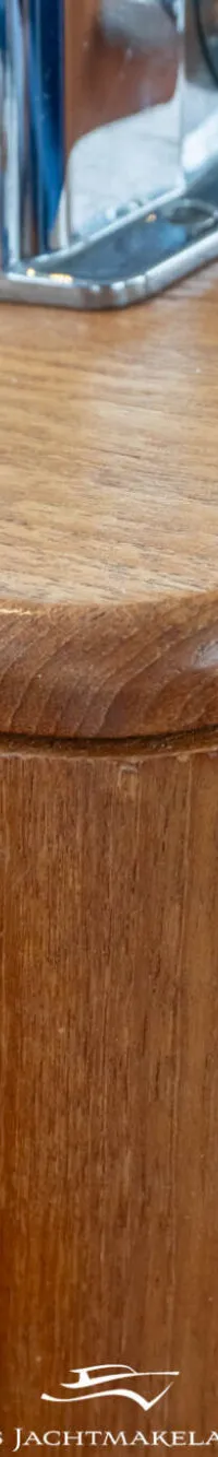 Een close-up van een houten kastje met een afgeronde bovenrand en een metalen handvat bovenaan.