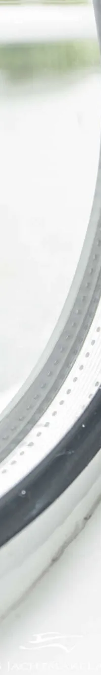 Een close-up van een rond patrijspoort met een zilveren rand en een zwarte rubberen afdichting.