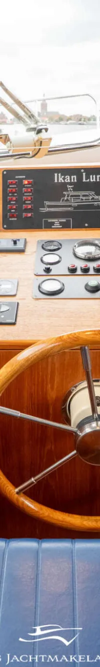 Een houten stuurwiel en een blauwe gestreepte bank in de kajuit van een boot. — Van Vossen Van Vossen Patrouille 10.50 OK
