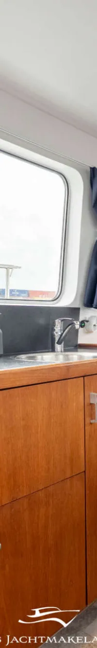 Een interieur van een boot met een houten keukenblok, een blauwe bank en een stuurstand.