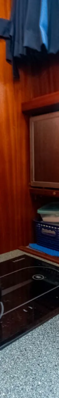 Een zilverkleurige waterkoker staat op een zwarte kookplaat in een houten kajuit met een ingebouwde magnetron.
