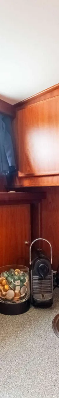Een houten kombuis met een aanrecht, spoelbak, kraan, koffiezetapparaat, capsulehouder en papieren handdoekhouder.