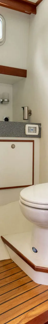 Een badkamer met een toilet, wastafel en houten vloer, gezien door een deuropening.