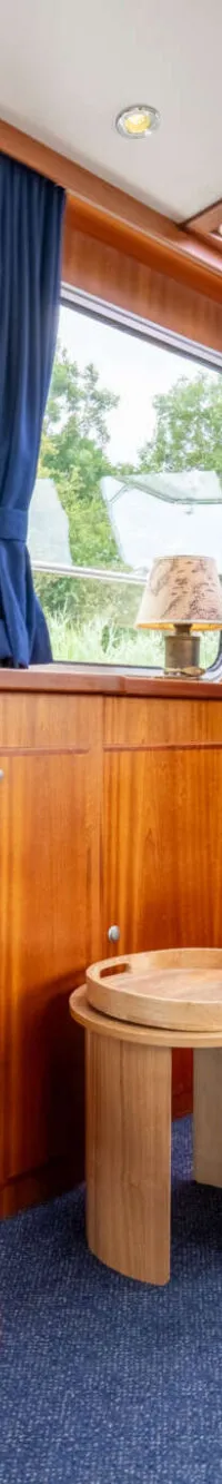 Een interieur van een boot met houten wanden, blauwe gordijnen en een blauwe vloerbedekking. — Brandsma Brandsma 11.00 OK SP