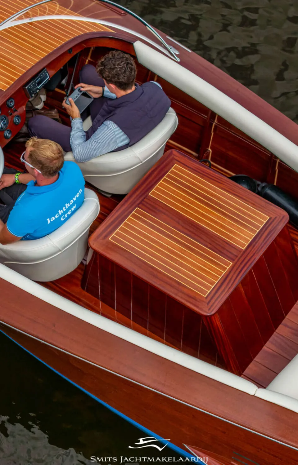 Een bovenaanzicht van een houten boot met twee mannen aan boord, waarvan één aan het stuur zit. — Divank Divank Uscire 635