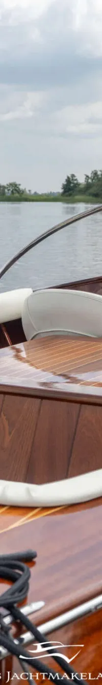 Een houten motorboot met een wit stuur en beige bekleding ligt aangemeerd aan een houten steiger. — Divank Divank Uscire 635