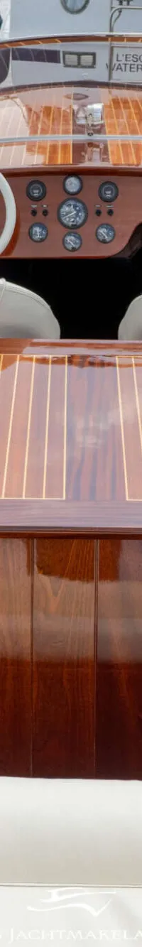Een houten boot met een glanzende afwerking en lichte bekleding ligt aan een houten steiger. — Divank Divank Uscire 635