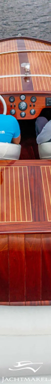 Twee mannen zitten in een houten boot met witte bekleding, varend op donker water. — Divank Divank Uscire 635