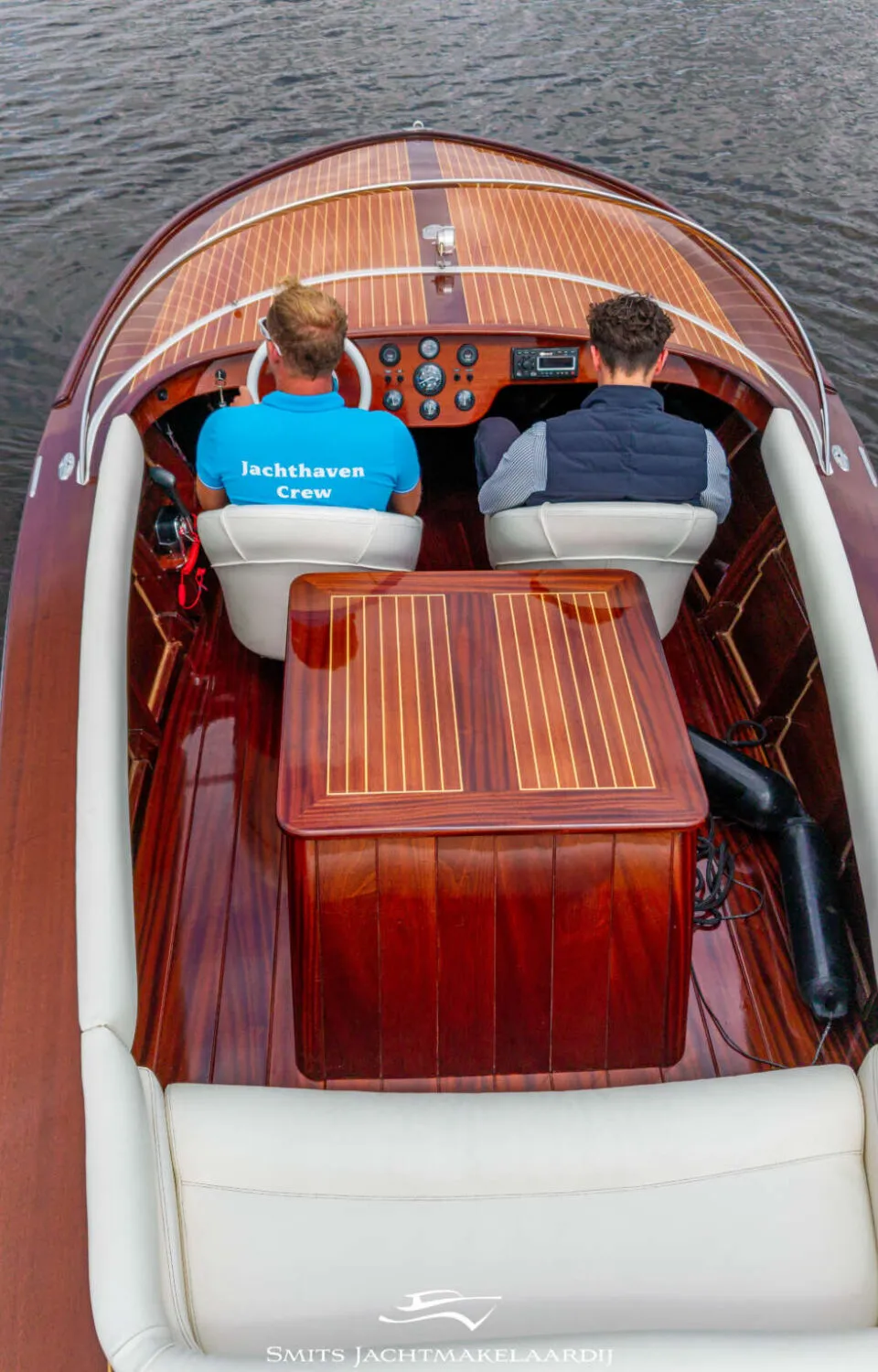 Twee mannen zitten in een houten boot met witte bekleding, varend op donker water. — Divank Divank Uscire 635