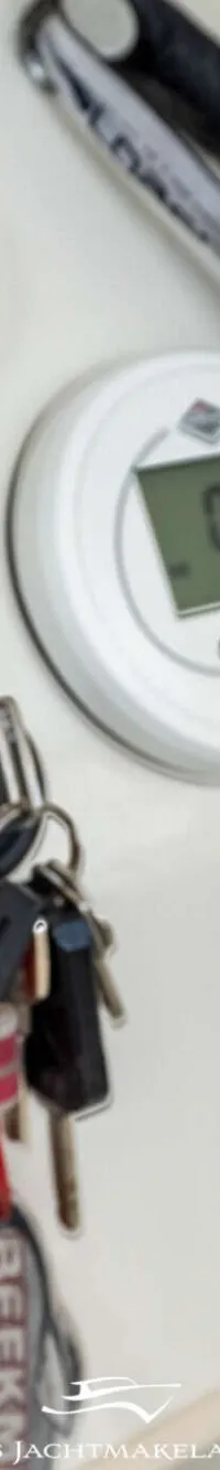 Op de foto is een deel van een zwart stuurwiel, een wit digitaal display met "0.7" erop, en een sleutelbos te zien.