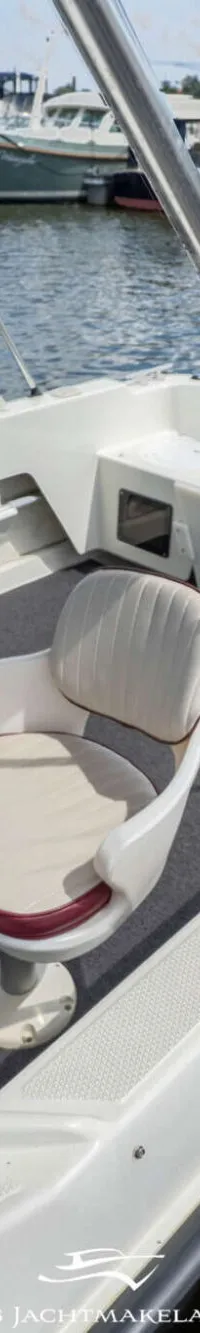 Een witte boot met een zwarte Mercury buitenboordmotor ligt afgemeerd aan een houten steiger.