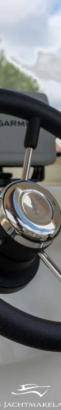 Een zwart stuurwiel met chromen spaken en een Garmin-apparaat op het dashboard van een boot. — Smartliner Smartliner 19 Cuddy