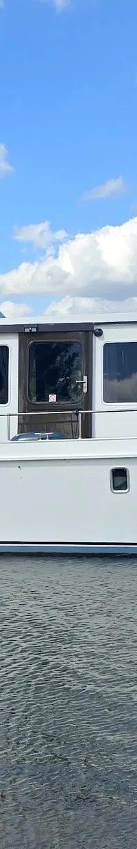 Een witte motorboot met de naam "Bellejan" en "MARHEN 1500 OSAK" op de romp vaart op water onder een blauwe lucht met wolken.