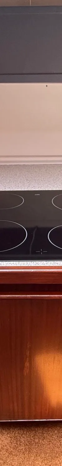 Een kombuis met een kookplaat, een Philips airfryer en houten kasten.