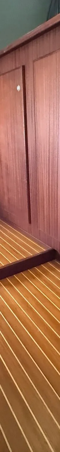 Een interieur met houten wanden en vloer, een wit radiatorpaneel en een rode brandblusser.
