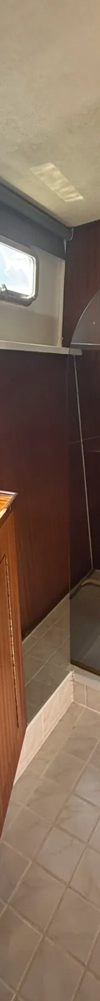 De foto toont een badkamer met een wastafel, een douchecabine en een houten meubel met lades.
