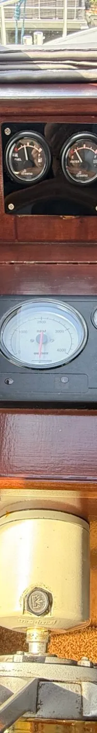 Een houten dashboard met diverse meters, schakelaars en bedieningshendels is zichtbaar.
