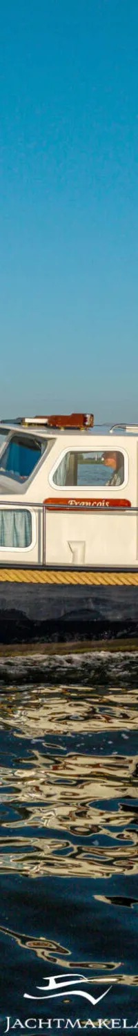 Een witte motorboot met een donkere romp vaart over rustig water onder een helderblauwe lucht. — Dompvlet Dompvlet 9.00 AK