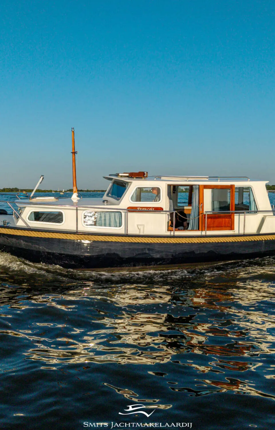 Een witte motorboot met een donkere romp vaart over rustig water onder een helderblauwe lucht. — Dompvlet Dompvlet 9.00 AK