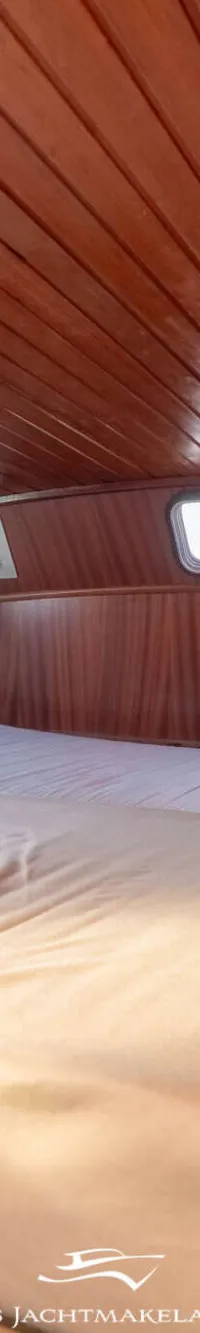 Een houten kajuit met twee bedden, blauwe gordijnen en een klein raam met uitzicht op een boot. — Dompvlet Dompvlet 9.00 AK