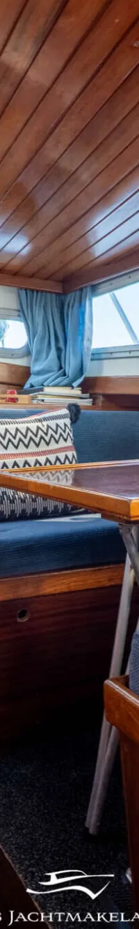 Een close-up van een scheepsmotor met blauwe onderdelen, diverse kabels en leidingen, en een geïsoleerde uitlaatpijp.