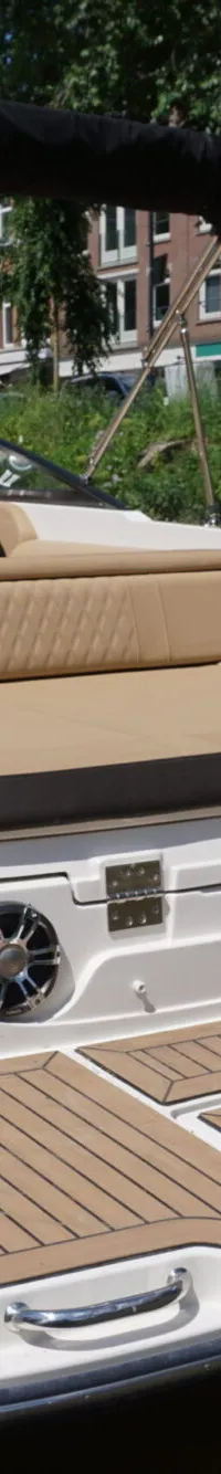 Een witte boot met beige bekleding en een zwarte biminitop ligt aangemeerd, met "SLX 250" op de spiegel. — Sea Ray 250 SLX