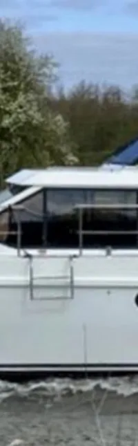 Een witte motorboot met de naam "ANTARIS" vaart op het water, met een donkerblauwe kap en ramen.