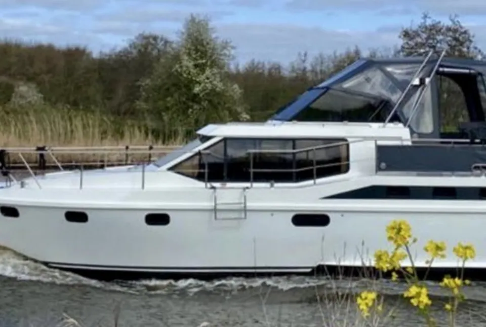 Een witte motorboot met de naam "ANTARIS" vaart op het water, met een donkerblauwe kap en ramen.