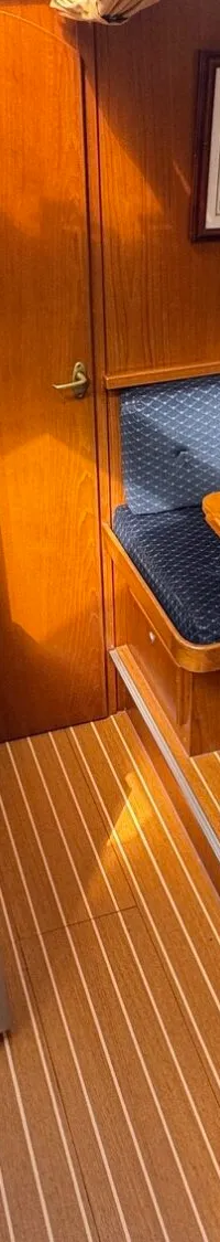 De foto toont een interieur van een boot met een kombuis, een eettafel met zitbanken en een houten vloer.