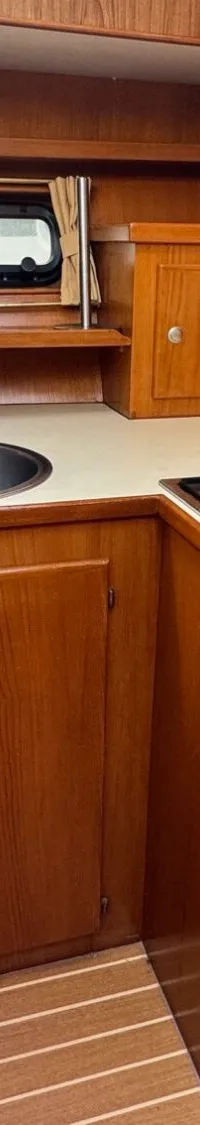 Een kombuis met een aanrecht, spoelbak, gasfornuis, koelkast, magnetron en koffiezetapparaat.