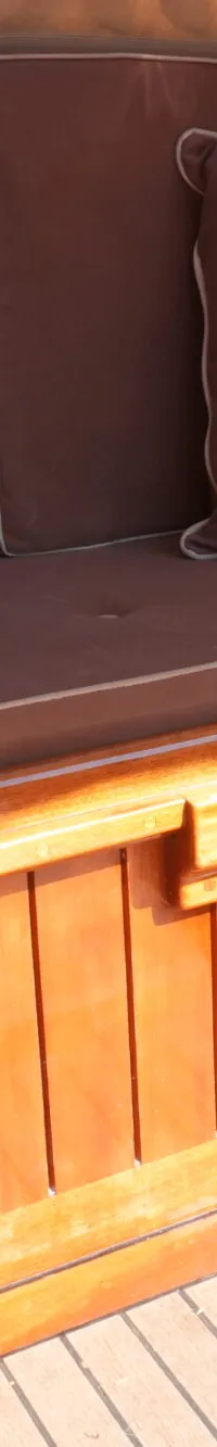 Een detailfoto van een bootinterieur met bruine kussens en houten panelen en vloer.