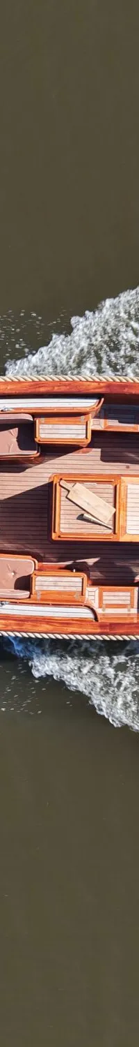 Een houten boot met een persoon aan het roer vaart over het water, gezien van bovenaf. — Wester Engh Wester Engh 7.80 Open