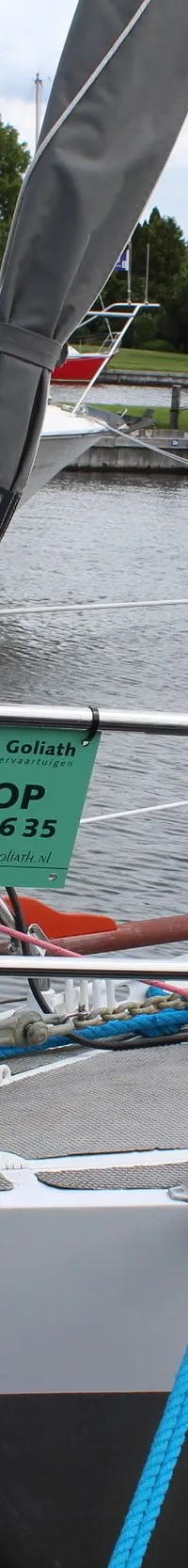 De boeg van een witte zeilboot met een anker, blauwe stootwil en een "TE KOOP" bord hangt aan de reling. — Ovni 32