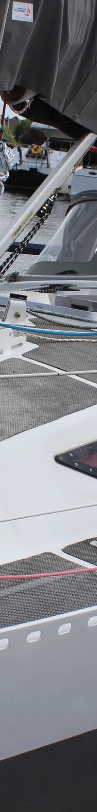 Een witte zeilboot met grijze romp, grijze sprayhood en grijze zeilhuik ligt afgemeerd aan een houten steiger. — Ovni 32