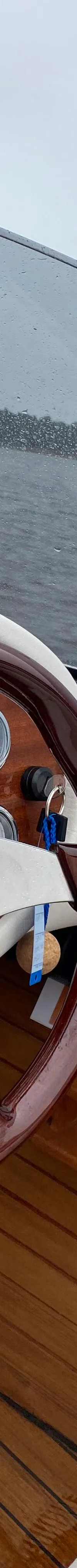 Een houten stuurwiel en dashboard met meters, een gashendel en een Frauscher 757 brochure zijn zichtbaar.