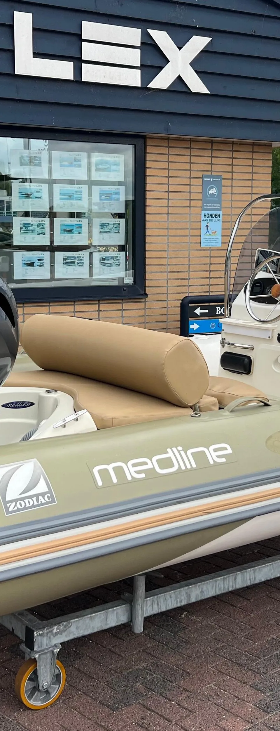 Een Zodiac Medline rubberboot met een Yamaha buitenboordmotor staat op een trailer voor een gebouw met de tekst "NAVILEX".