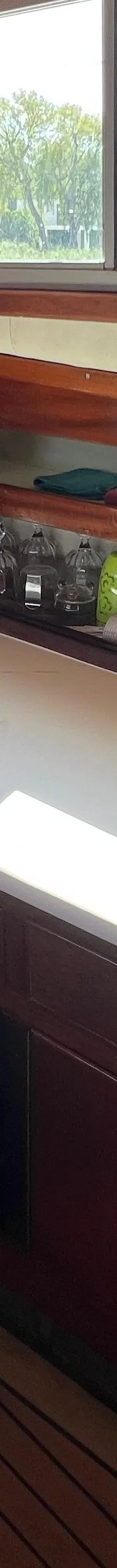 De foto toont een kombuis met een fornuis, spoelbak, koelkast, opbergruimte en een klok aan de wand.