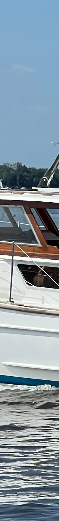 Een witte motorboot met een blauwe kap en een Nederlandse vlag vaart op het water. — Kruiser Polyflash 950