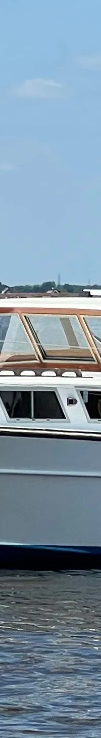 Een witte motorboot met de naam "Jenneke" vaart op een waterweg onder een blauwe lucht. — Kruiser Polyflash 950