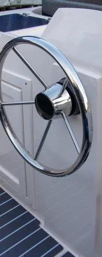 De foto toont een stuurstand met een chromen stuurwiel, een gashendel en een contactsleutel met dodemanskoord.