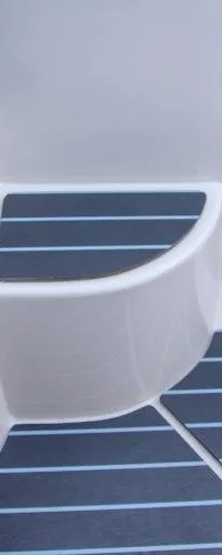 Een detailfoto van een donkergrijze zitting met een wit onderstel en een donkergrijze vloer met lichtblauwe strepen.