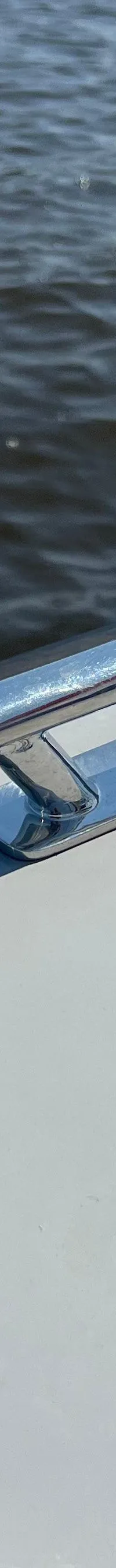 Een detailfoto van een bootdek met een kikker, een handvat, een dieselvulopening en een afgedekte aansluiting, met water op…